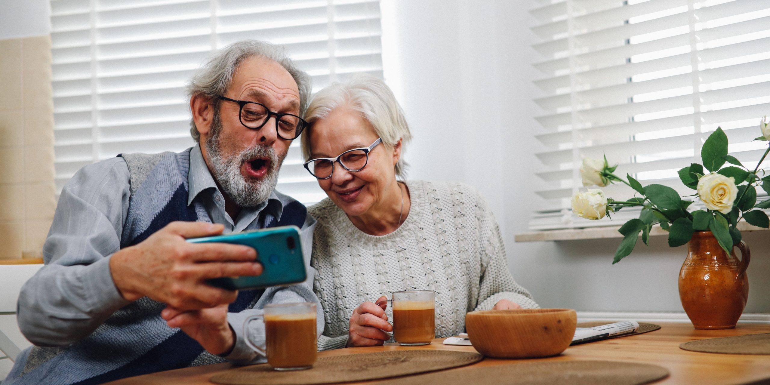 Dos personas mayores chequeando alegremente el celular.